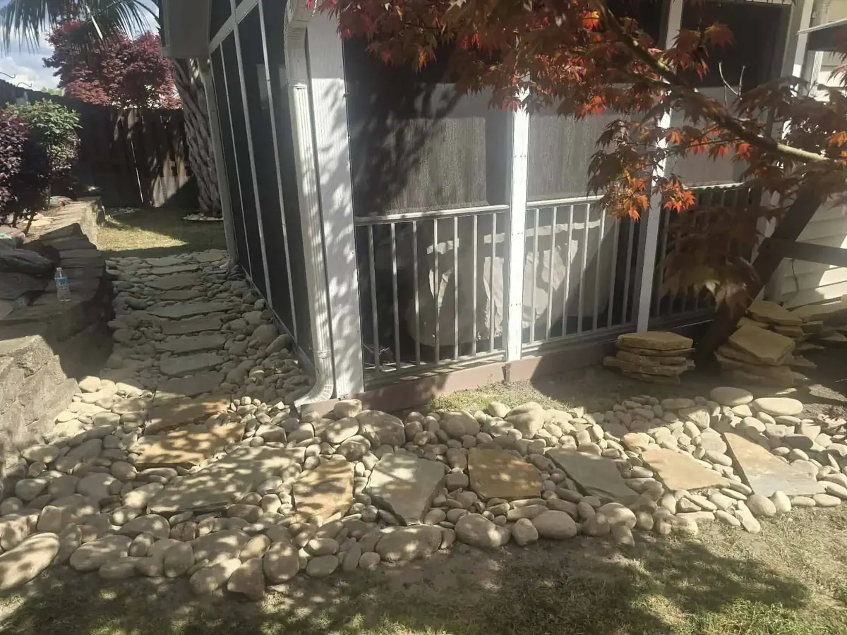 Finished yard drainage project with stone and graded beds beside a home