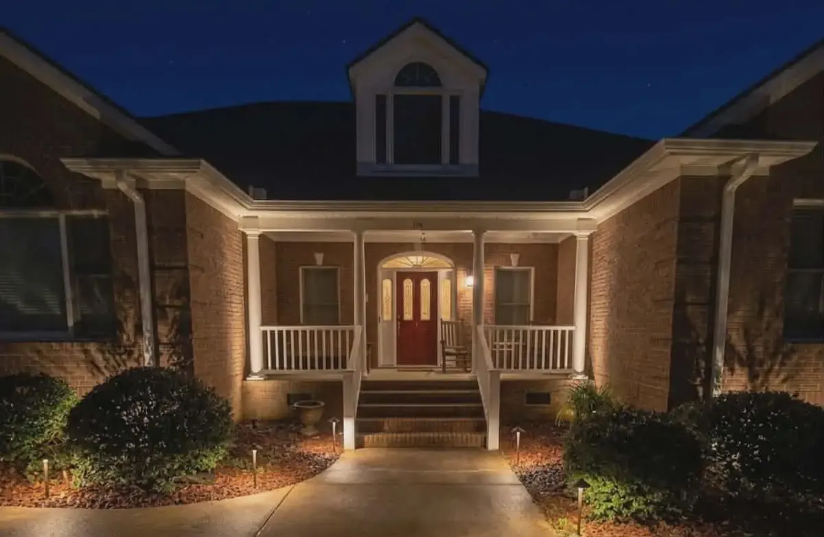 Brick home with warm landscape lighting along the walkway and front beds